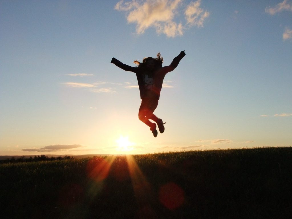 An energetic woman jumping high during sunrise.