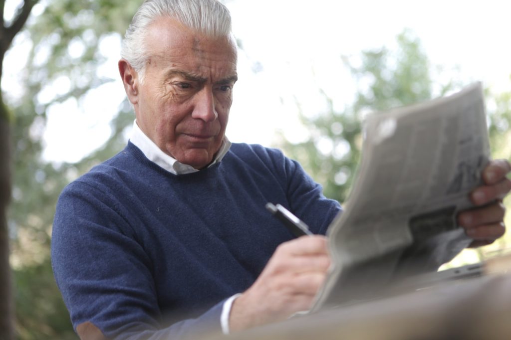 man focusing on a newspaper crossword puzzle